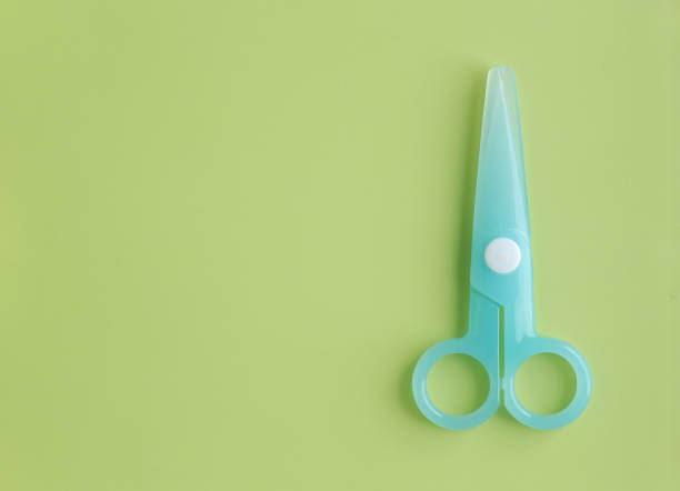 istock Cyan Plastic children safety scissors on green background. 903257458
