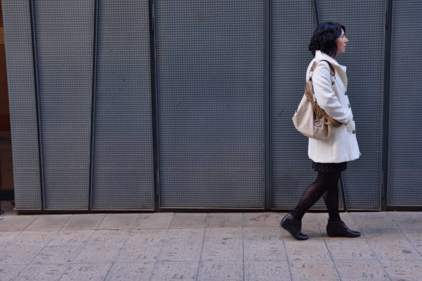 istock woman walking next to an iron texture wall 903264616