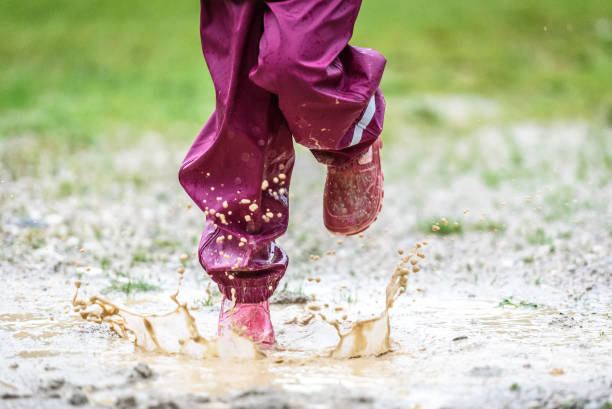 istock Children in rubber boots and rain clothes jumping in puddle. 903266258