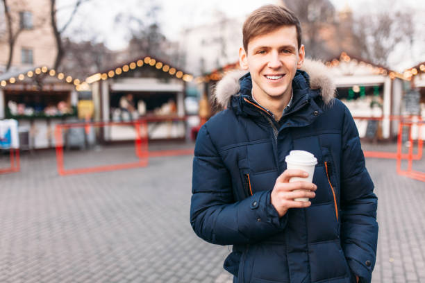 istock a handsome man in a jacket holding a plastic Cup, drinking coffee or tea, it's cold outside 903267314