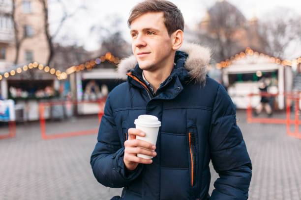 istock a handsome man in a jacket holding a plastic Cup, drinking coffee or tea, it's cold outside 903267318