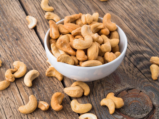 istock Cashew nuts in  white cup on brown wooden background, side view 903270048