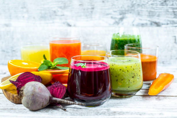 Fresh detox juices from fruit and vegetables in glass bottles on a wooden background stock photo