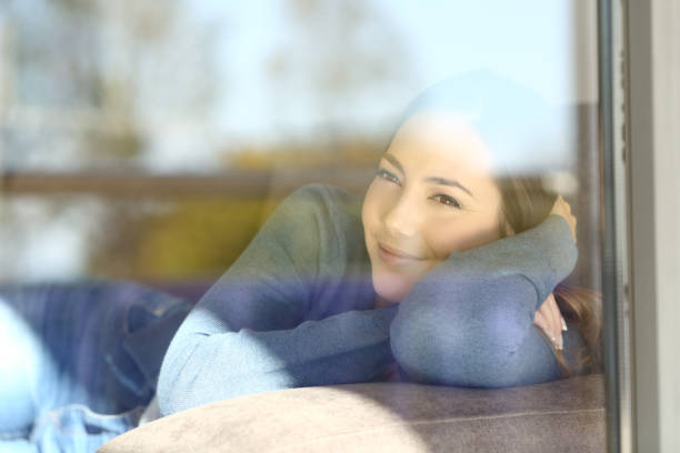 istock Relaxed lady looking through a window at home 903270860