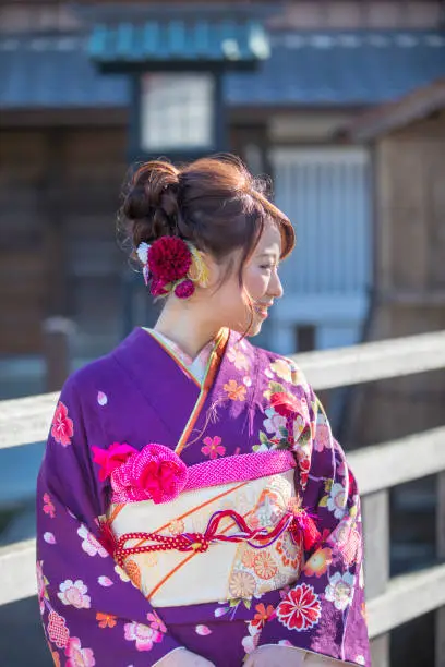 Young woman in furisode kimono standing in traditional Japanese town