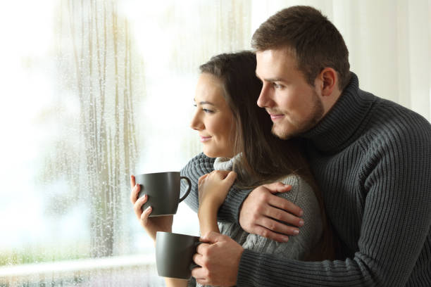 пара, смотря в окно в дождливый день - window rain winter house стоковые фото и изображения