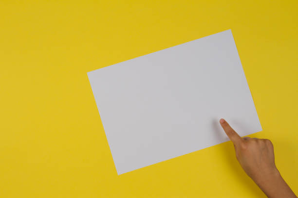 istock Kids hand finger pointing to white blank paper card on yellow background 903289708