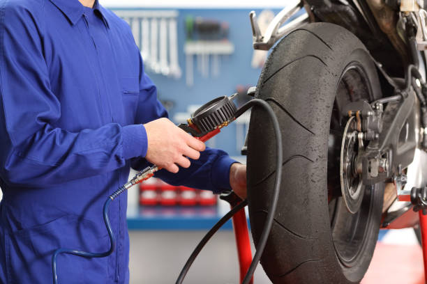 Motorbike mechanic checking tires air pressure Close up of a motorbike mechanic hand checking tires air with a pressure gauge in a workshop bike workshop stock pictures, royalty-free photos & images