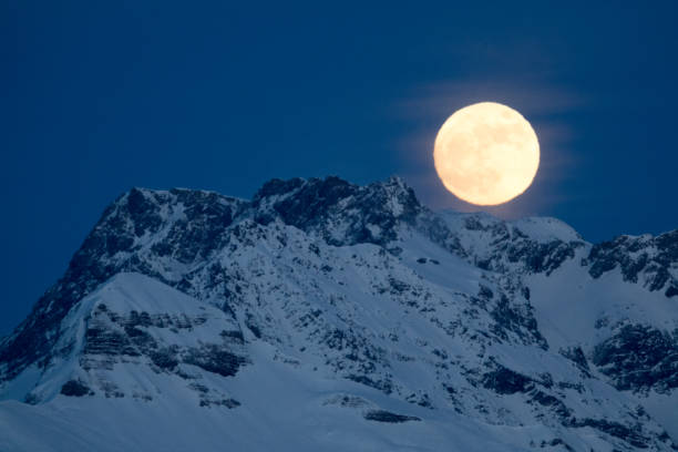 full moon rising over winter mountain landscape in the Swiss Alps between Klosters and Maienfeld