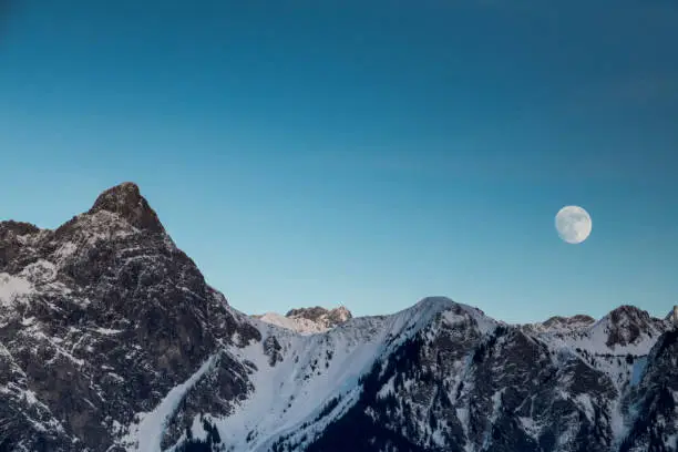 full moon rising over winter mountain landscape in the Swiss Alps between Klosters and Maienfeld