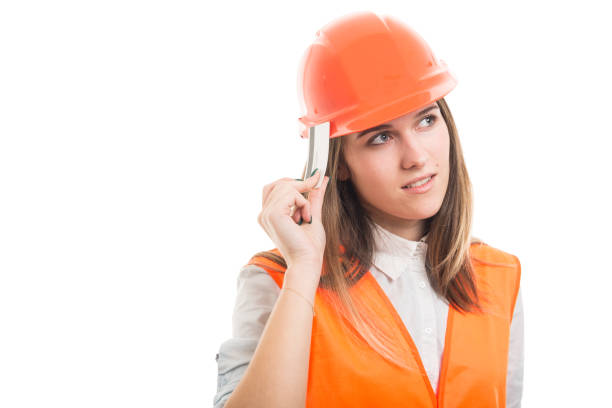 Pensive pretty female constructor with credit card looking far away on white background with copyspace
