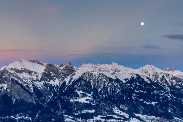 full moon rising over winter mountain landscape in the Swiss Alps between Klosters and Maienfeld