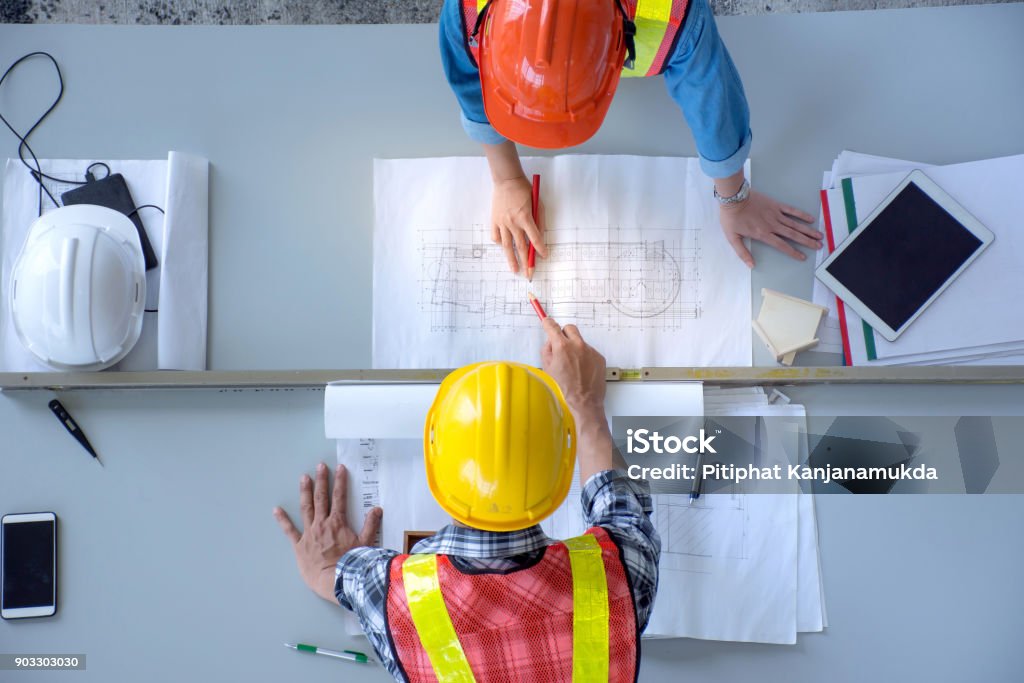 La vista dall'alto del gruppo di ingegneri è la riunione, la pianificazione dei lavori di costruzione, l'aspetto dei piani cartacei in cantiere, la vista aerea - Foto stock royalty-free di Industria edile