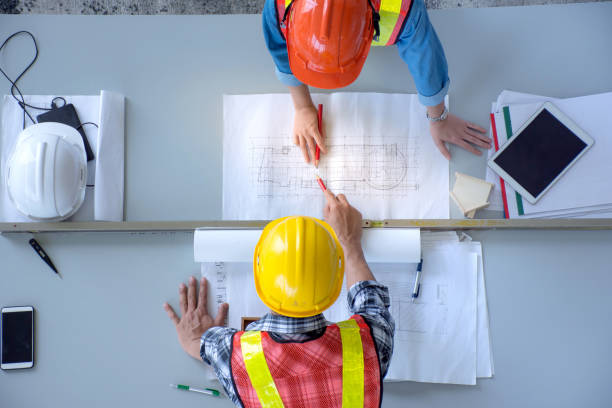 エンジニア リング チームのグループの平面図を会議、建設工事を計画、建設現場、俯瞰で机上の計画を探しています。 - construction worker manual worker construction group of people ストックフォトと画像
