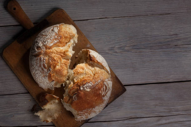 istock Torned homemade bread loaf on old cutting board with a free space on the right 903323694