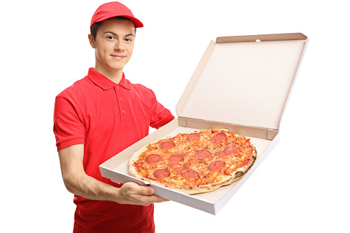 Teenage pizza delivery boy showing a pizza inside a box isolated on white background