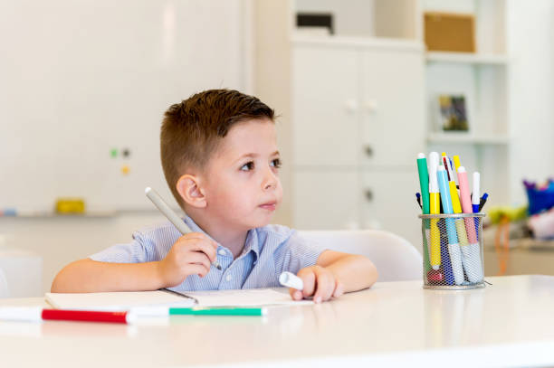 istock child preschooler boy drawing on booklet ,while sitting on the d 903327116
