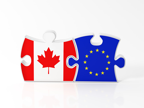 Jigsaw puzzle pieces textured with Canadian and European Union flags on white. Horizontal composition with copy space. Clipping path is included.