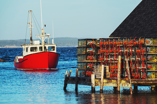 A lobster boat approaches an iconic wharf in Peggy's Cove, Nova Scotia.
