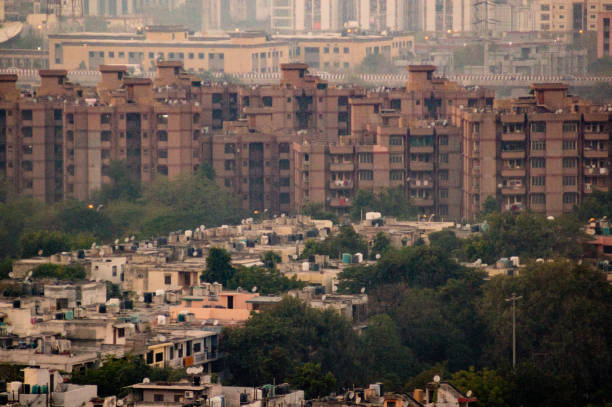 aerial shot of housing apartments in Noida Aerial shot of housing apartments in Noida towering over old fashioned independent homes. These apartments are critical to house the ever growing population of the city delhi metro stock pictures, royalty-free photos & images