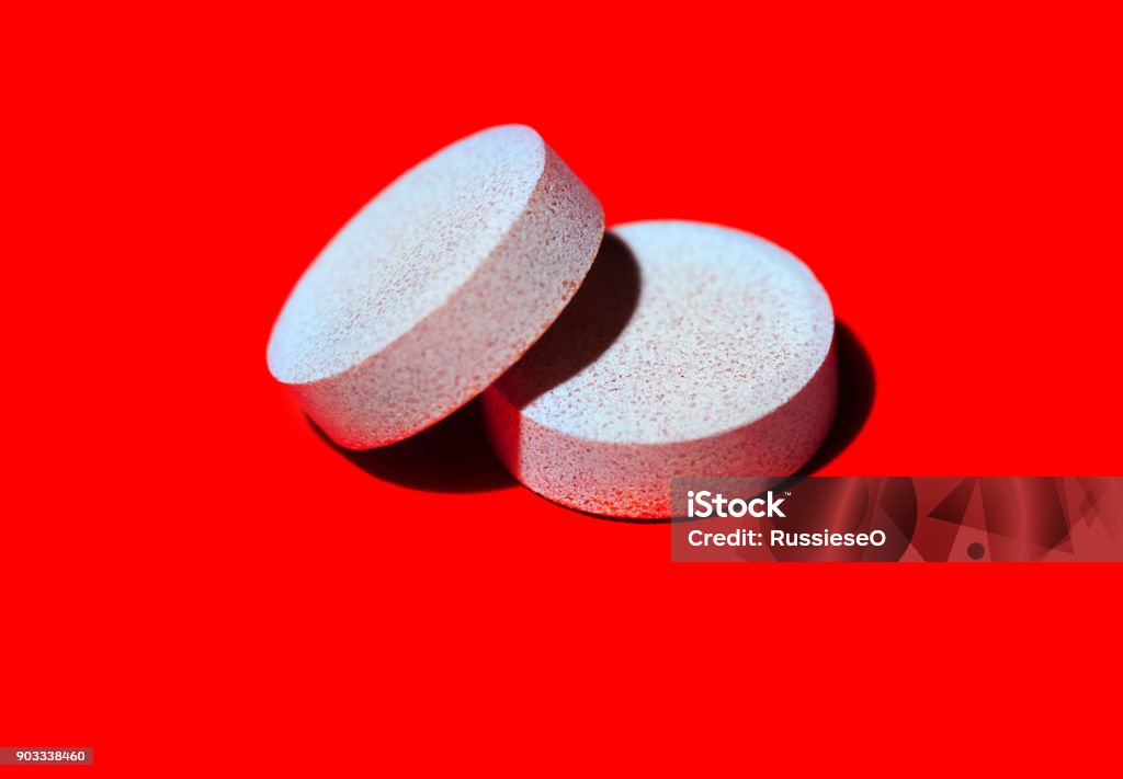 multivitamins on red background two white multivitamins on red background Addiction Stock Photo