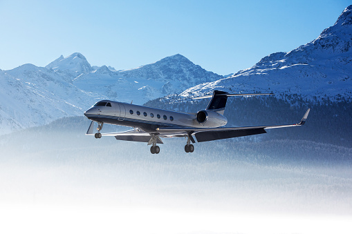 Business Jet approaching in front of snow covered mountains.