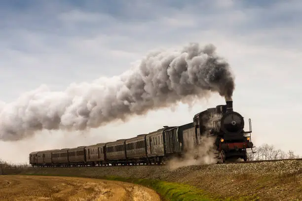 Vintage black steam train running on railway in countryside