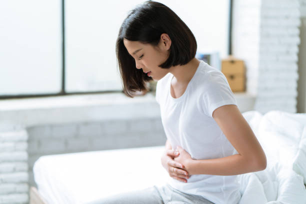 las mujeres asiáticas su estómago duele duro ella se despierta en medio de la noche mientras duerme. - belly ache fotografías e imágenes de stock