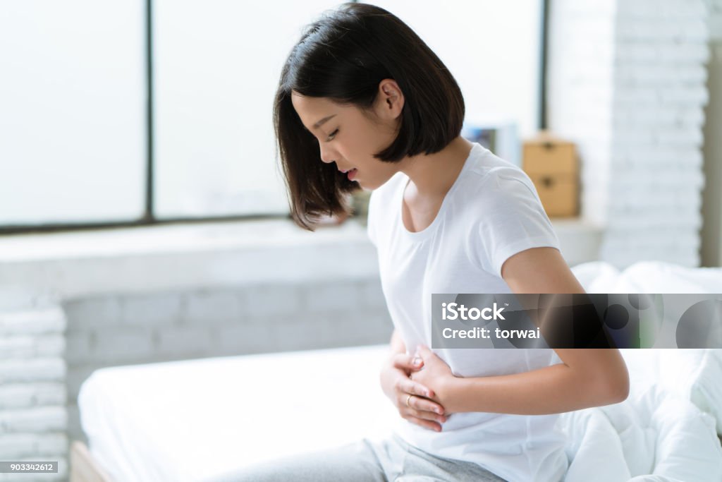 Asian women her stomach aches hard She wakes up in the middle of the night while she sleeps. Abdomen Stock Photo