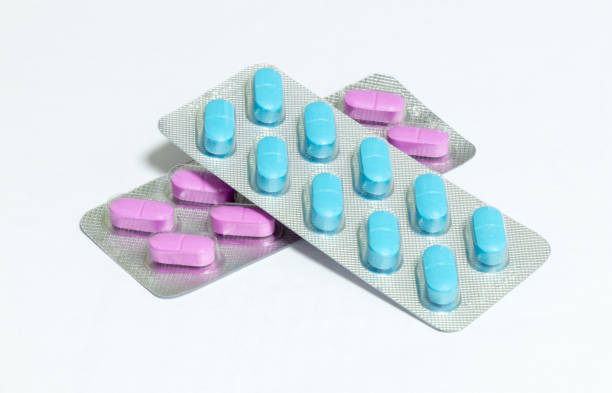 istock One package with pink  and one package with blue oblong pills isolated on a white background 903346502