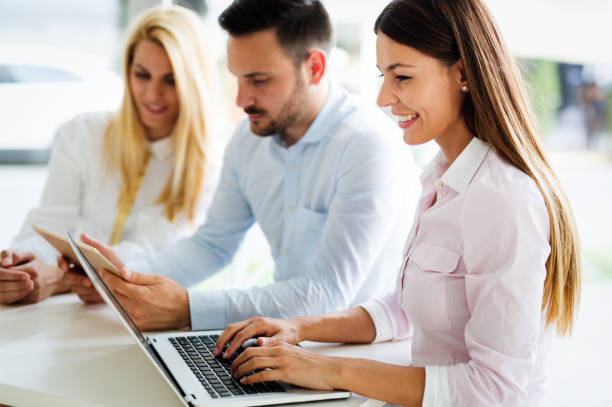 istock Three young smiling colleagues working together on laptop 903347414