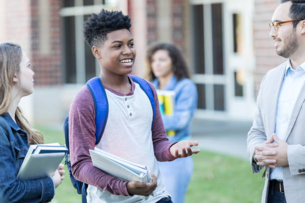 istock Students discussing something with high school teacher outdoors 903350766