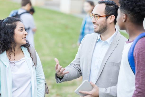 istock Hispanic male teacher explaining something to high school students 903350886