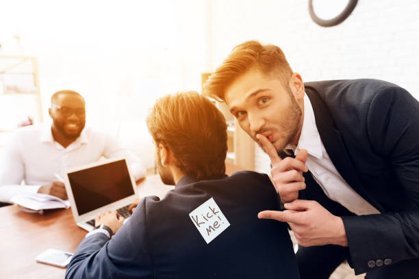 The men stuck a sticker on the back of another man. The men stuck a sticker on the back of another man. This is his business colleagues. They joked at him on April 1st. April Fools Pranks stock pictures, royalty-free photos & images