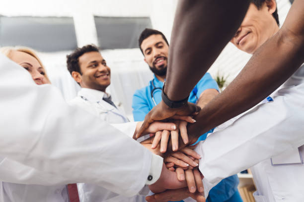 istock A group of doctors are holding each other's hands. 903354414