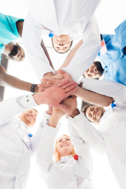 istock A group of doctors are holding each other's hands. 903354428