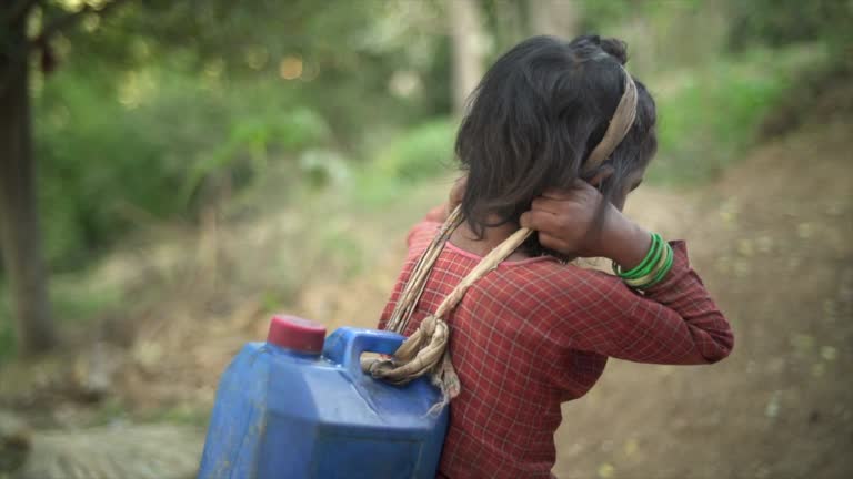Young Nepali girl carries large jug of water