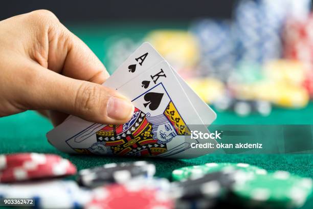 Gambling Hand Holding Poker Cards And Money Coins Chips Stock Photo - Download Image Now