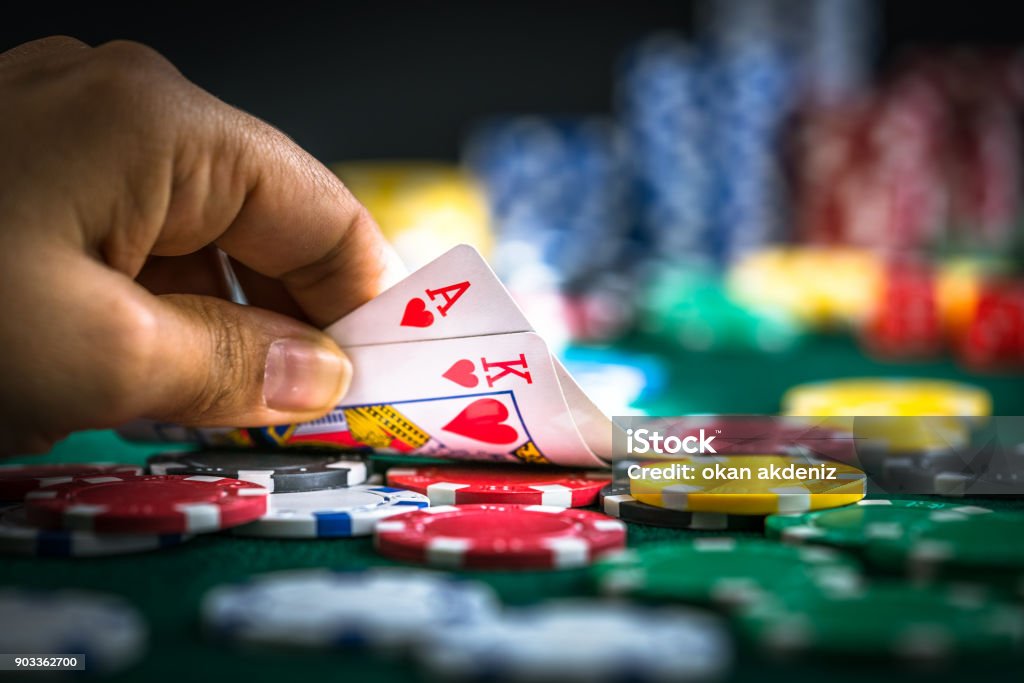 Gambling Hand Holding Poker Cards and Money Coins Chips Poker - Card Game Stock Photo