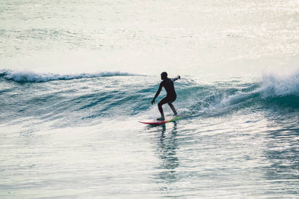istock Surfer in wetsuit ride on blue wave. Winter surfing in ocean 903362816