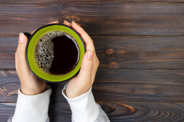 istock Female hands holding cup of coffee on rustic wooden table background 903369430