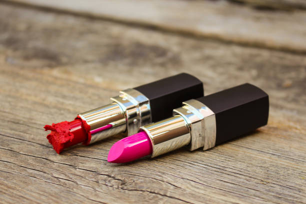 istock Broken red and new pink lipsticks on old wooden background. 903370200