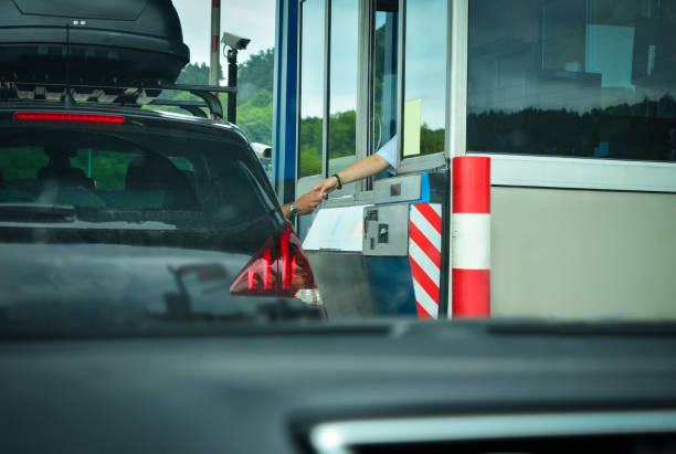 un uomo paga soldi a un cassiere per una strada a pedaggio - toll booth foto e immagini stock