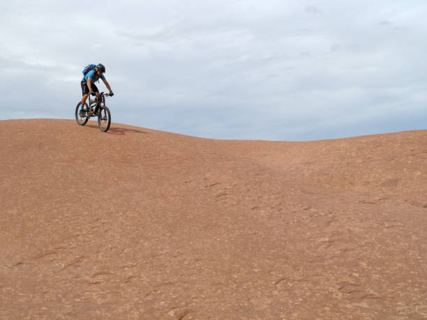 ciclista de montaña, montar a caballo cuesta abajo el famoso rocoso sendero, moab, estados unidos - slickrock trail fotografías e imágenes de stock