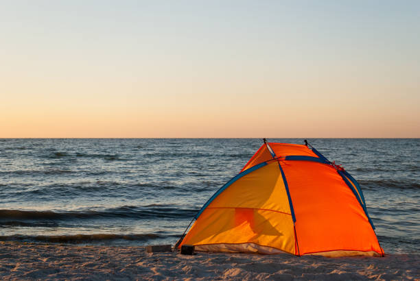 istock bright orange yellow tent empty on the seashore dawn 903382484