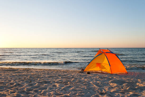 istock bright orange yellow tent empty on the seashore dawn 903382504