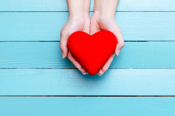 istock red heart in hands on a blue background 903386030