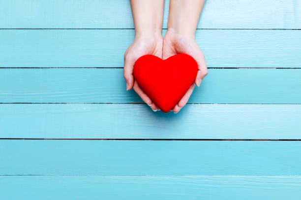 istock red heart in hands on a blue background 903386034