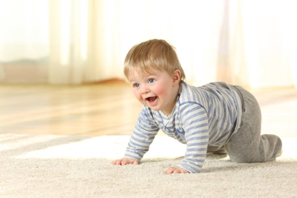 istock Happy baby crawling and laughing on a carpet 903387940