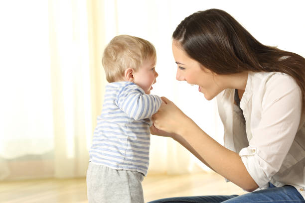 istock Mother helping her baby son in his first steps 903388812